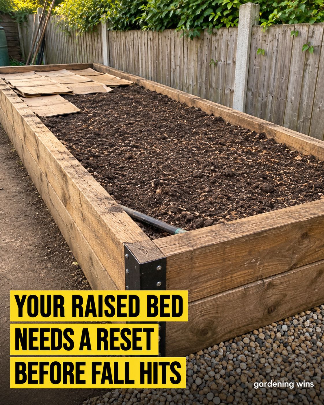 Wooden raised garden bed with cleared soil and cardboard over one end, with the words “Your raised bed needs a reset before fall hits.”